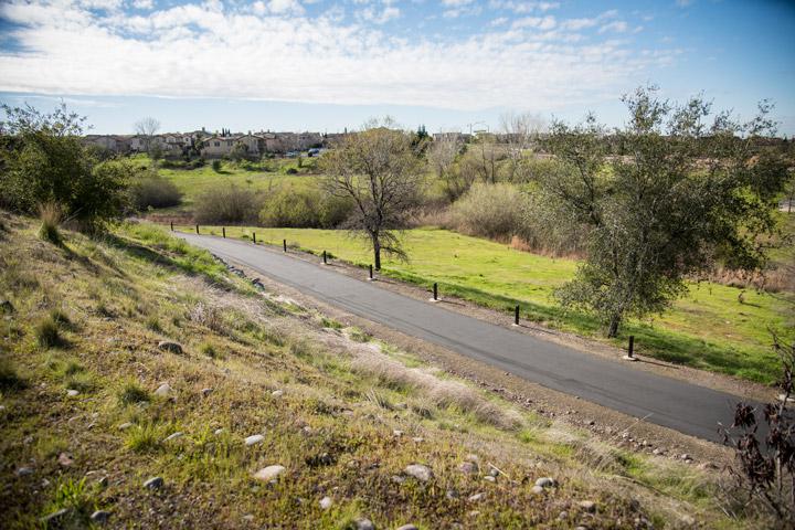 Whitney Ranch community asphalt walking trail with green grass and trees