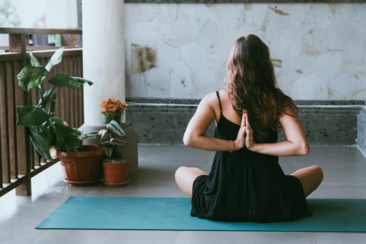 brunette woman doing yoga pose on mat next to houseplants