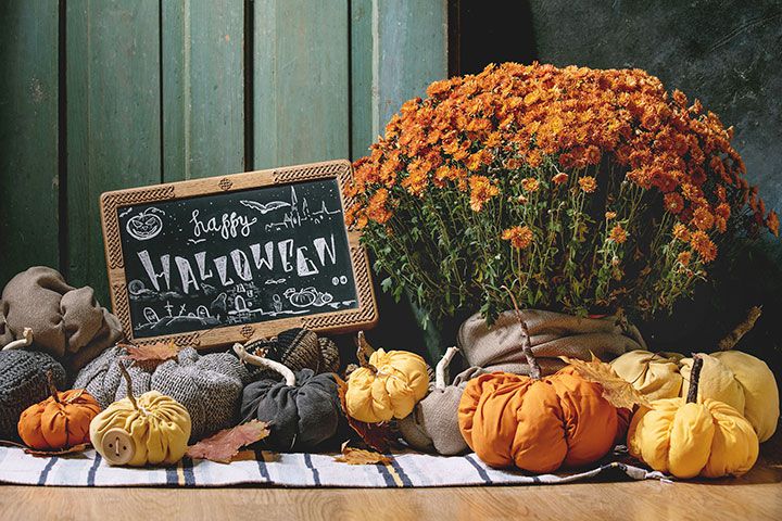 a fall inspired bouquet of orange and white pumpkins, orange and green flowers and a chalk board with festive writing wishing you a happy halloween