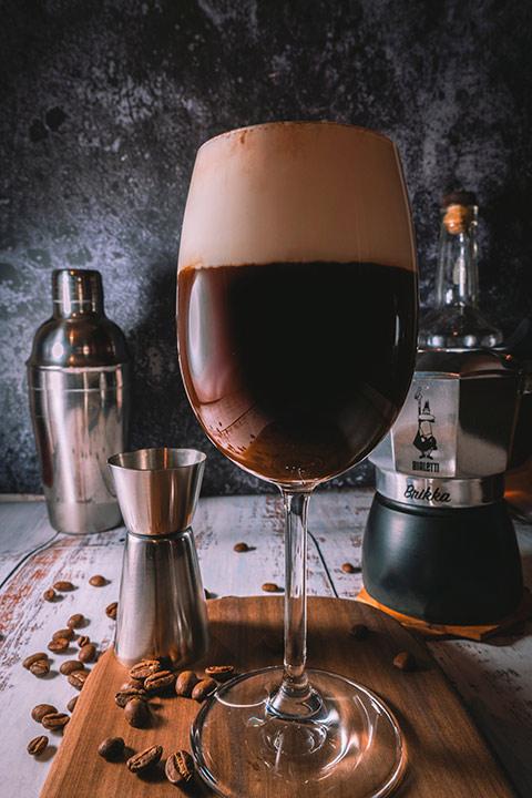 foamed Coffee in glass on wooden background