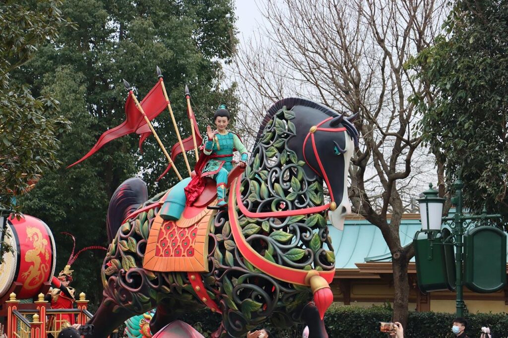 Mulan waves to guests as she proceeds in a Disney parade